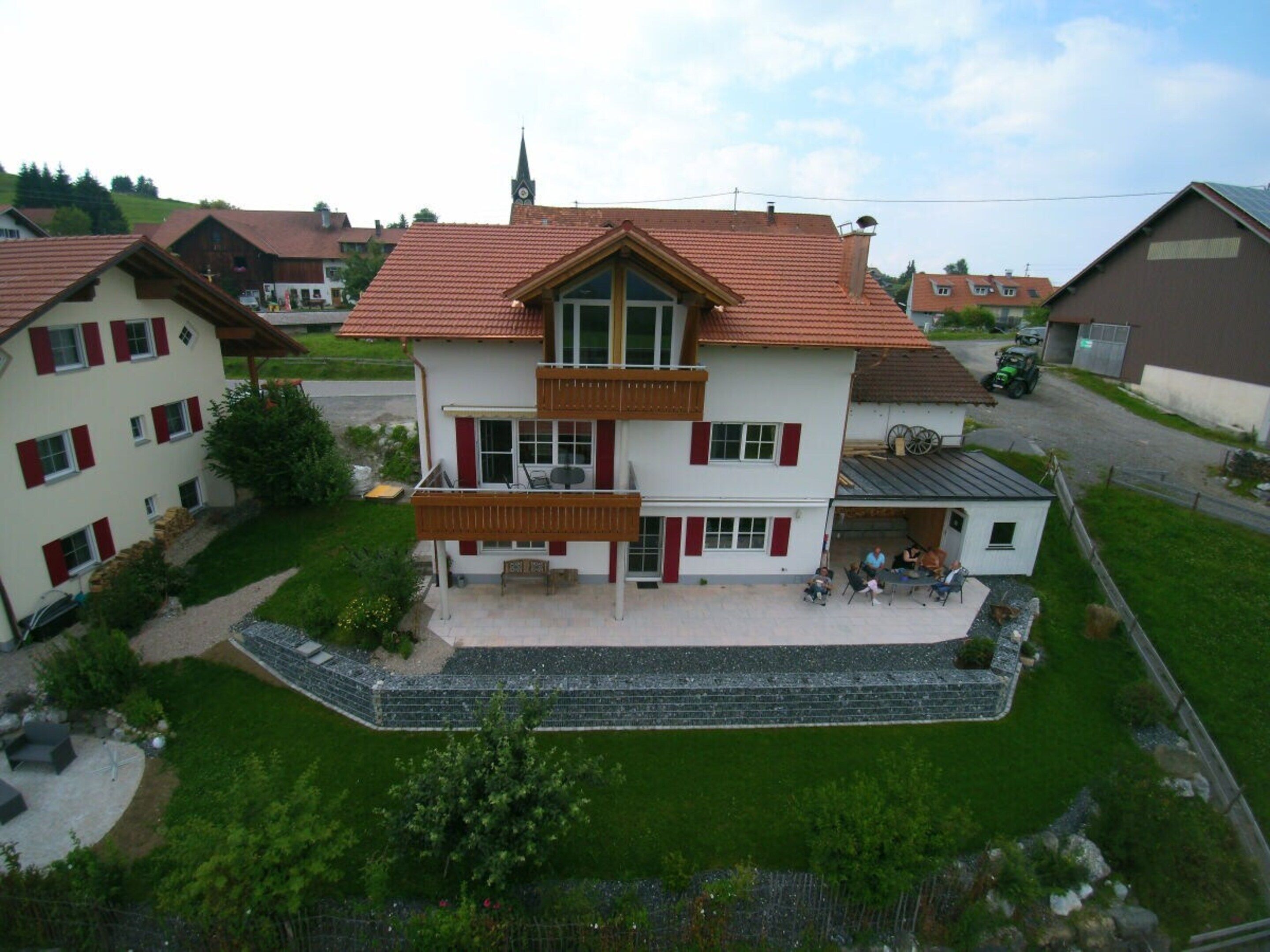 Ein mehrgeschossiges Wohngebäude mit Balkon, einer kleinen angebauten Garage und einem gepflegten Rasen.