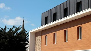 Un edificio moderno con fachada de madera y sección superior negra.