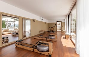 Habitación amplia con piso de madera, grandes espejos y equipo de ejercicio.