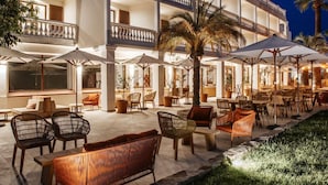 A multi-story hotel with outdoor seating and palm trees. - Domaine Du Mirage (Bormes-Les-Mimosas)