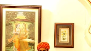 Un hombre está de pie detrás de un mostrador de recepción con obras de arte enmarcadas y una estatua en la pared.