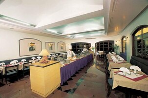 A restaurant with a long dining table, multiple chairs, and a buffet setup.