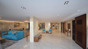 Eine großzügige Lobby mit einem blauen Sofa, einer hölzernen Bank und einer Sitzecke mit gemusterten Stühlen.