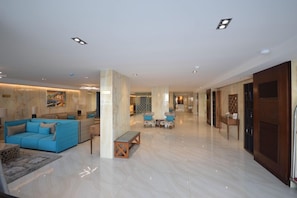 A spacious lobby with a blue sofa, a wooden bench, and a seating area with patterned chairs. - Rahhal Al Bahr Hotel Apartment (Jeddah)