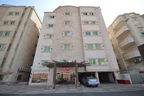 A multi-story hotel with a central entrance, balconies on the upper floors, and a parking area in front. - Rahhal Al Bahr Hotel Apartment (Jeddah)