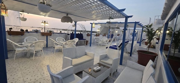 An outdoor seating area with wicker furniture, potted plants, and a view of the sea. - Rahhal Al Bahr Hotel Apartment (Jeddah)