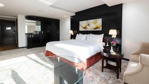 A modern hotel room with a large bed, a glass coffee table, a chair, and a painting on the wall. - Mira Hotel (Riyadh)