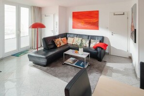 Una sala de estar moderna con un sofá modular, una mesa de centro y una lámpara de pie roja.