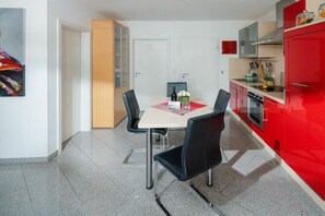 Una cocina funcional con una mesa de comedor, sillas y un refrigerador rojo.