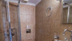 A bathroom with a glass shower enclosure, a white sink, and a toilet. - Niriides Apartaments (Symi)