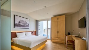 A modern hotel room with a large bed, a wooden desk, a flat-screen TV, and a framed picture on the wall. - Cubicity Nguyen Truong To (Ho Chi Minh)