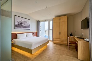 A modern hotel room with a large bed, a wooden desk, a flat-screen TV, and a framed picture on the wall. - Cubicity Nguyen Truong To (Ho Chi Minh)