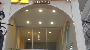 Exterior del hotel Cubicity con un llamativo letrero amarillo, entrada de vidrio y una escalera que conduce a la entrada.