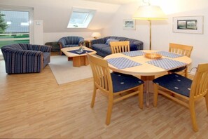 A cozy living room with a round dining table, striped sofas, and a large window. - 6 at Gmelinstraße 23 (Wyk auf Föhr)