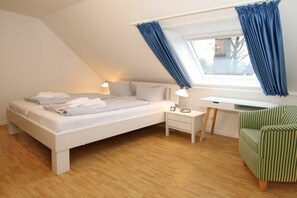 A bedroom with a bed, bedside tables, a desk, and a chair. - 6 at Gmelinstraße 23 (Wyk auf Föhr)
