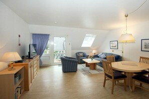 A furnished living room with a sofa, a coffee table, a dining table with chairs, a lamp, and a television. - 6 at Gmelinstraße 23 (Wyk auf Föhr)