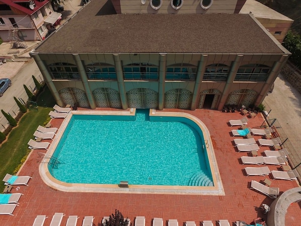 A swimming pool with lounge chairs and a building with large windows. - Sarot Termal Park Resort & Spa (Mudurnu)