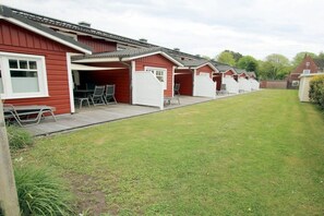 A row of red buildings with attached patios, each with a table and chairs. - Brandgans at Susanne-Fischer Weg 43 (Wyk auf Föhr)