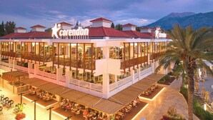 A multi-story hotel with a prominent 'corendon' sign, outdoor seating, and a view of mountains in the background. - Hydros Beach Resort (Kemer)