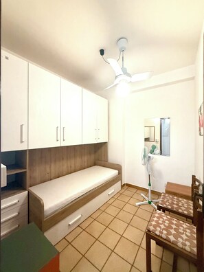 A small, well-lit room with a bed, a desk, a chair, and a ceiling fan. - Vacation rental sleeping 5 or 6 in the center of Marina di Ragusa. (Marina di Ragusa)