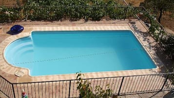 Una piscina rectangular con una solana empavedada alrededor.
