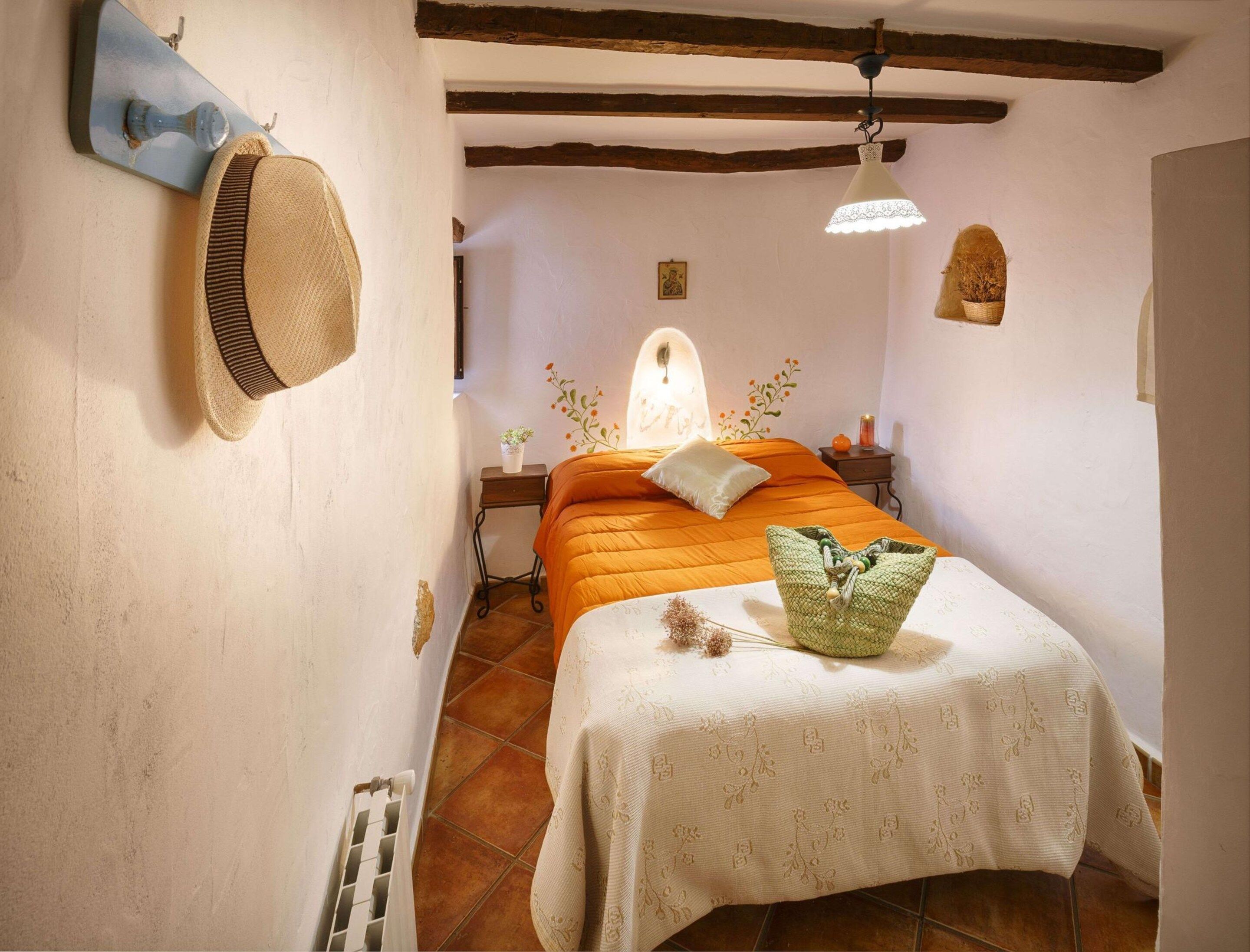 Un dormitorio con cama, mesita de noche, lámpara y perchero en la pared.