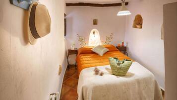 Un dormitorio con cama, mesita de noche, lámpara y perchero en la pared.