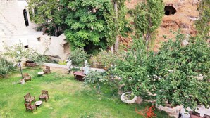 Un espacio al aire libre con un muro de piedra, una mesita y varias sillas.