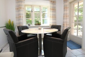 Ein Essbereich mit einem runden Tisch, vier Stühlen und einem fenster mit Vorhängen.