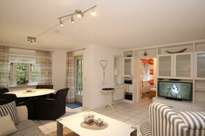 A living room with a television, a dining table, and a sofa. - 2 - Rungholtstraße 3c (Wyk auf Föhr)