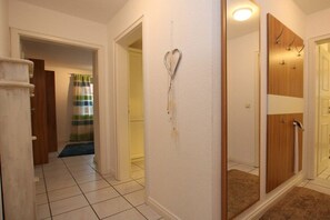 Ein Flur mit Duschbereich, einem Spiegel und einer Tür zu einem weiteren Raum.