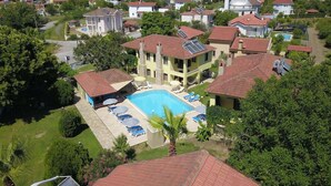 Zona residencial con piscina, varias casas y un edificio grande con techo rojo.