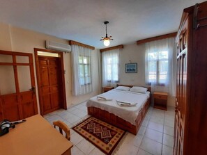 A bedroom with a bed, a desk, and a chair. There is a ceiling fan, a window with curtains, and a wall-mounted air conditioner. - Adilan Villas And Apartments (Ortaca)