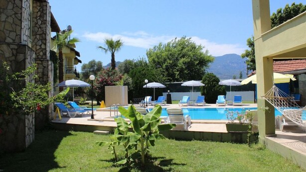 Un área de piscina con sillones de descanso, sombrillas y una hamaca.