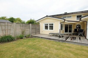 A two-story house with a patio area, a wooden fence, and a grassy yard. - Seestern at Susanne-Fischer Weg 25 (Wyk auf Föhr)