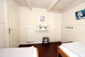 A room with two beds, a radiator, a small stool, and a painting on the wall. - Seestern at Susanne-Fischer Weg 25 (Wyk auf Föhr)