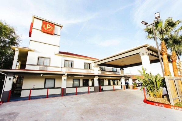 Ein mehrstöckiges Hotel mit Parkplatz und Feuerwehrzufahrt.