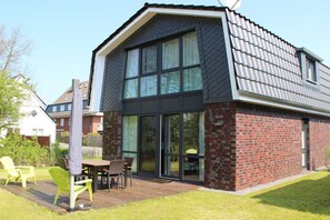 A modern house with a large glass door entrance, a deck with outdoor furniture, and a brick exterior. - Holiday home in Cuxhaven with Wi-Fi (Cuxhaven)