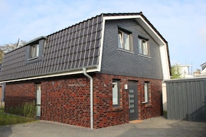 A two-story brick house with a dark roof, a small front porch, and a garage door. - Holiday home in Cuxhaven with Wi-Fi (Cuxhaven)