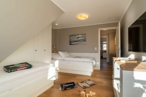 A modern bedroom with a bed, a bedside table, a game of Scrabble, and a bookshelf. - Holiday home in Borgsum with swimming pool (Borgsum)