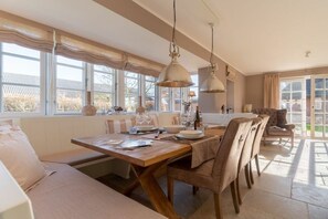 A dining area with a wooden table, chairs, and hanging pendant lights. - Holiday home in Borgsum with swimming pool (Borgsum)