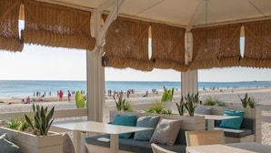An outdoor seating area with tables and chairs, overlooking a beach. - Aldiana Club Andalusien (Chiclana de la Frontera)