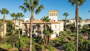 A building with a central courtyard surrounded by palm trees, a tower, and a clear sky. - Aldiana Club Andalusien (Chiclana de la Frontera)