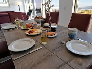 A dining table set with plates, cutlery, and various food items, with a view of the outdoors through large windows. - 49.6.n Dwarsloper (Wangerland)