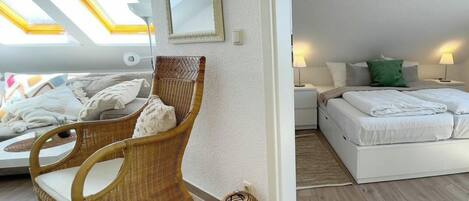 Una habitación con cama, una silla, mesita de noche, lámpara y ventana con vistas.