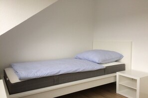 A small, single-bed room with a white headboard and a white nightstand. - Holiday apartment with 1 bedroom (Cuxhaven)