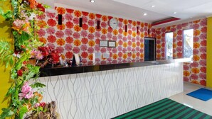 A reception area with a floral wall design, a reception desk, and a clock. - OYO 3428 Hotel Marimar (Palangkaraya)