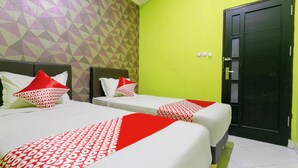 A hotel room with two beds, each with red and white bedding, a geometric patterned wall, and a green accent wall. - OYO 3428 Hotel Marimar (Palangkaraya)