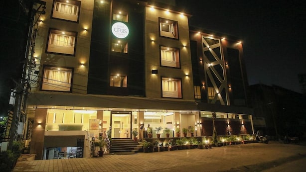 Een hotel met meerdere verdiepingen, een goed verlichte ingang en een bord met de naam 'Citrus Hotel'.