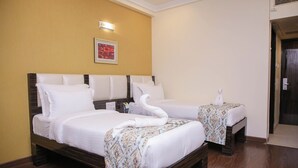Een hotelkamer met twee bedden, een hoofdeinde, een wandlamp en een ingelijst schilderij.
